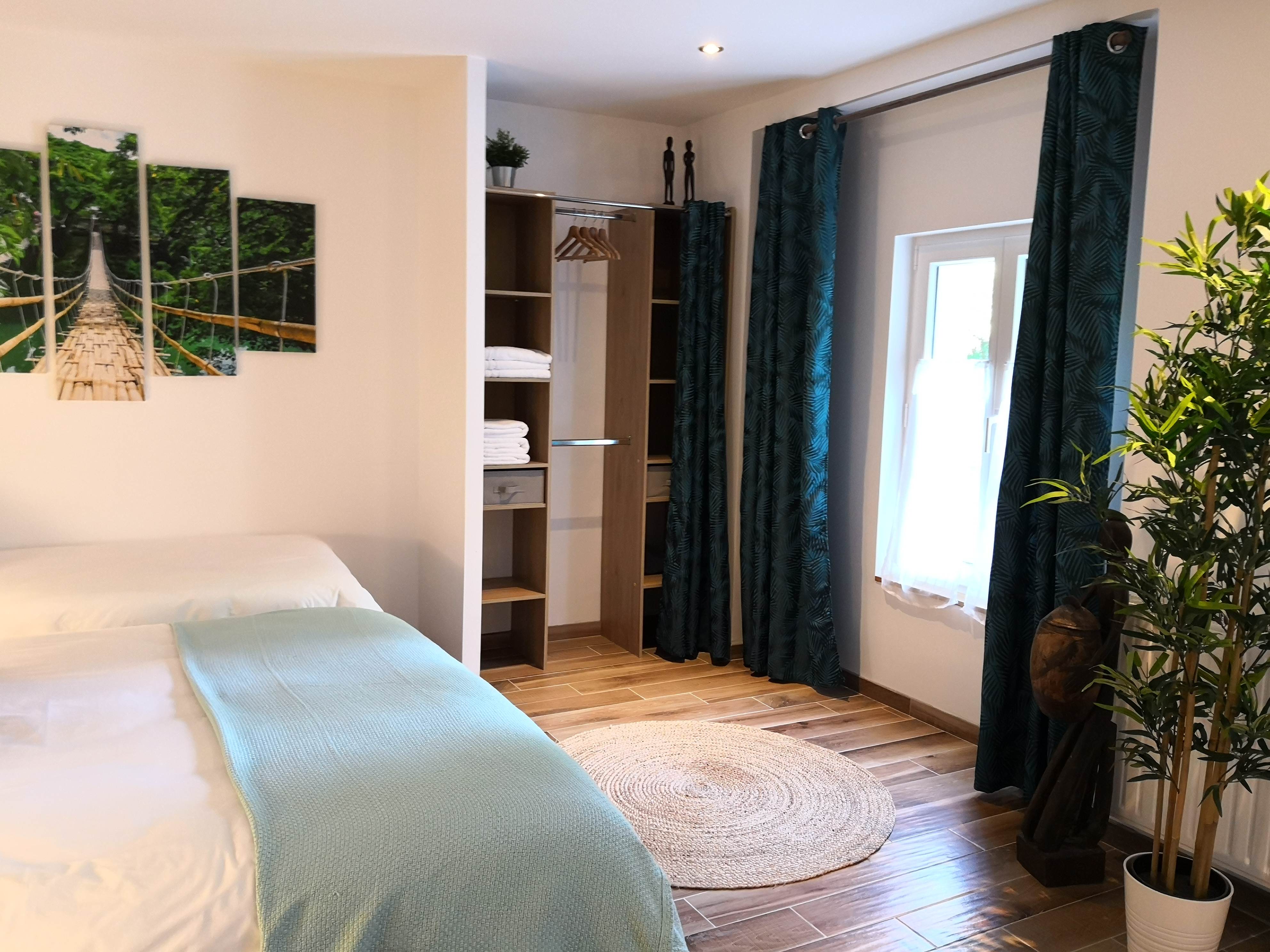 Armoire ouverte avec serviettes pliées, toile d'un pont suspendu au mur et rideaux à motif de palmes.
